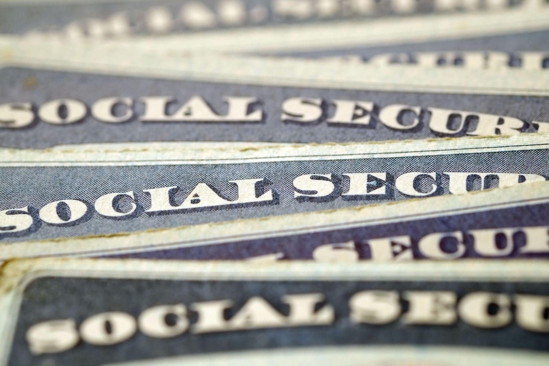 A close-up of multiple stacked Social Security cards showing the blue text on a white background.