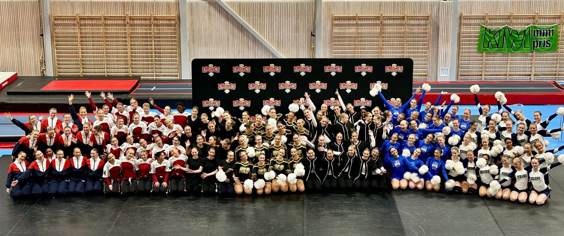 Large group in coordinated red, black, gold, and blue outfits posing for a team photo indoors