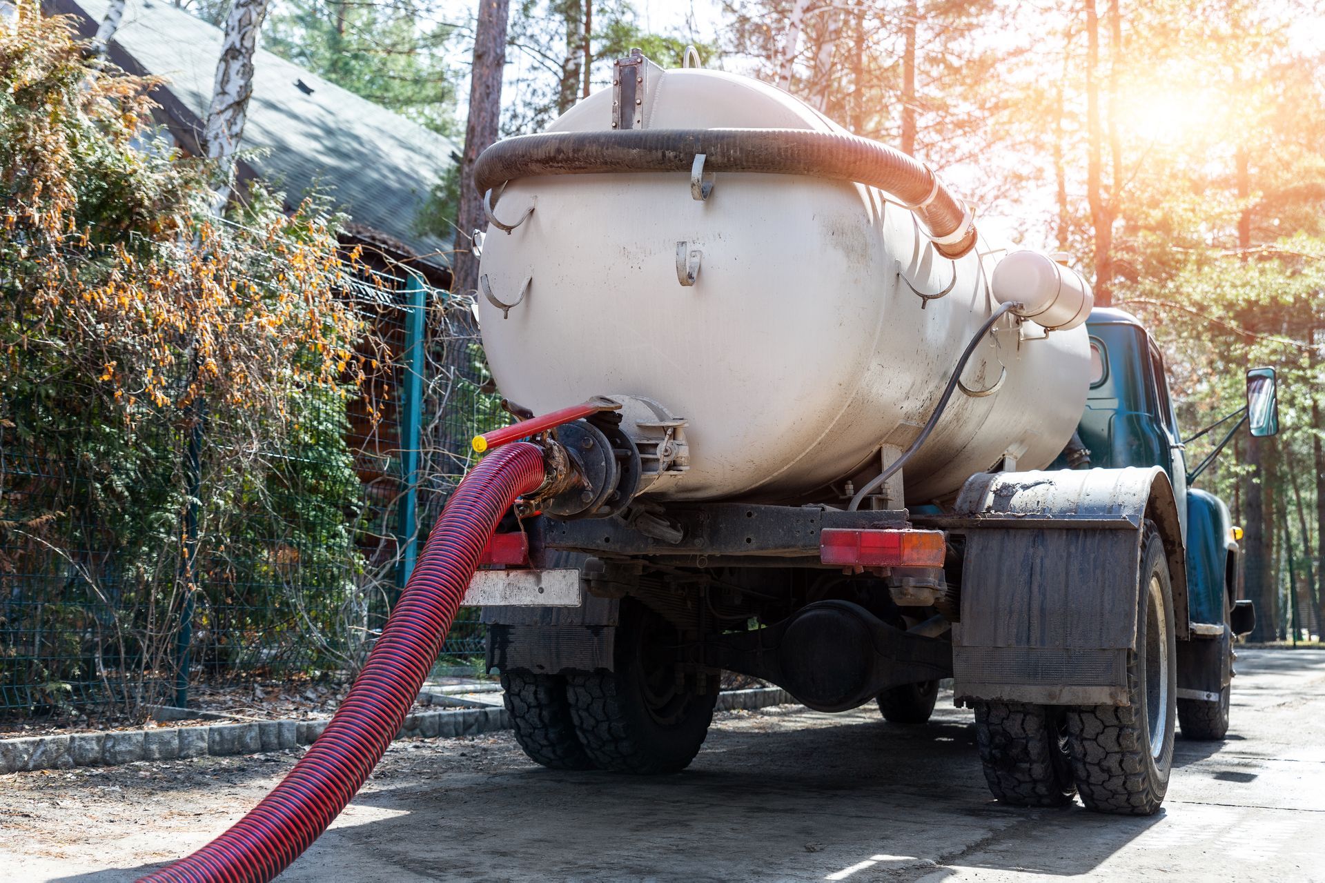Concrete mixer truck spraying red hose in a sunny outdoor work area