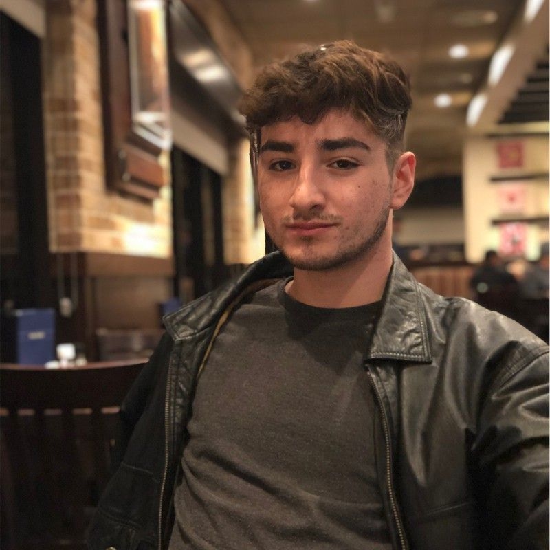 A young man wearing a leather jacket and a grey shirt