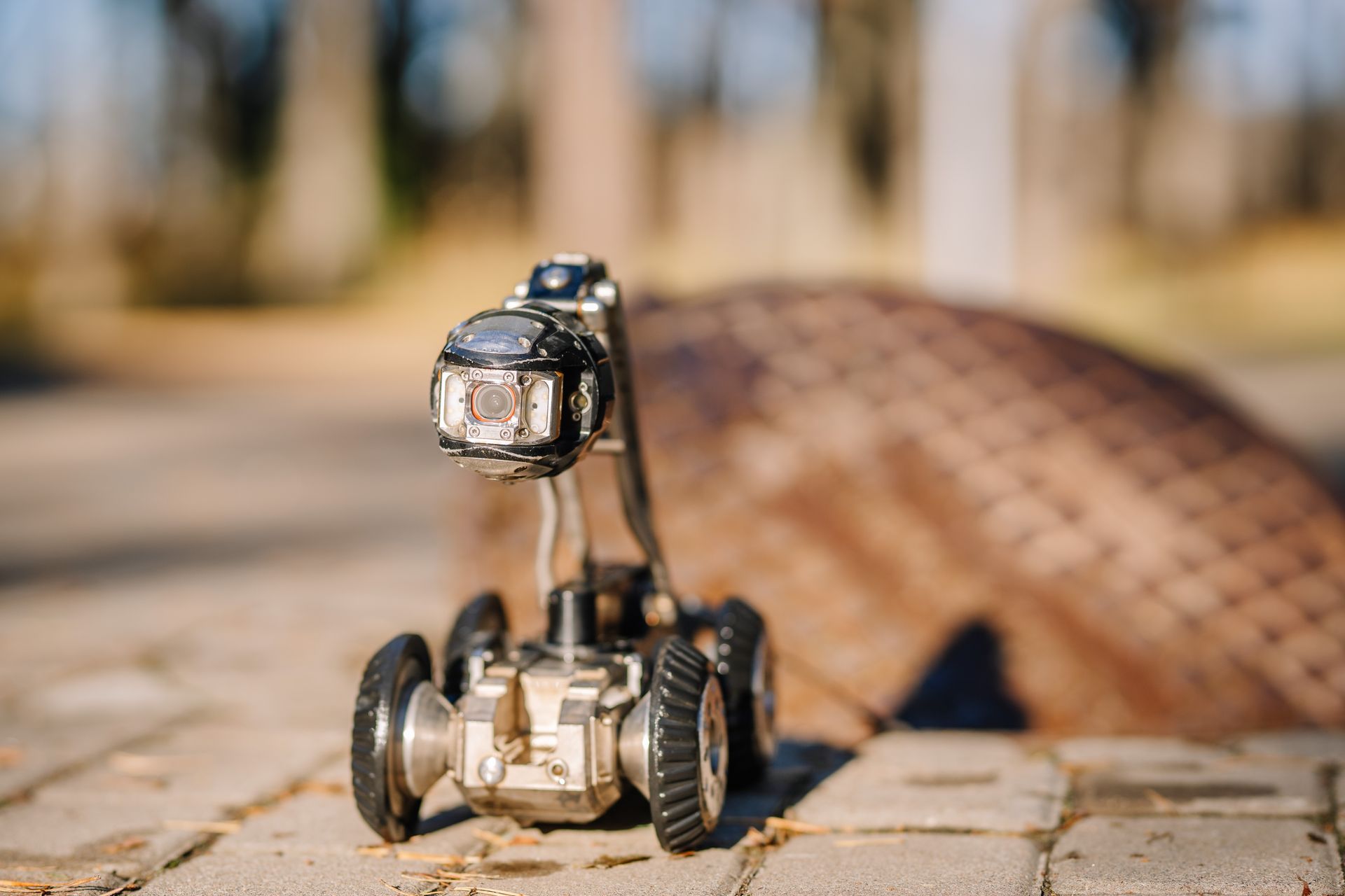 Small robot toy on a brick path with a blurred background and warm sunlight