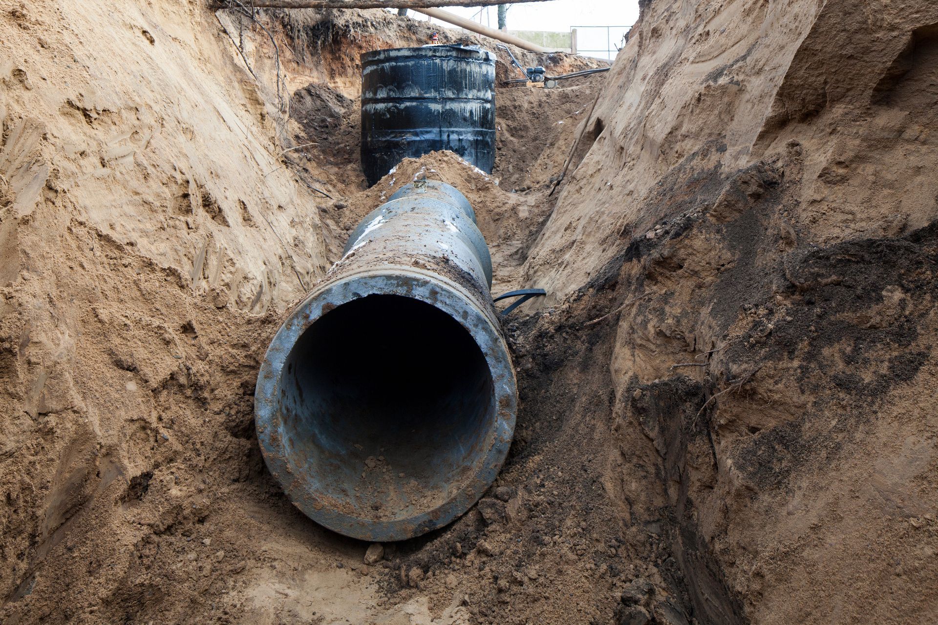 Large metal pipeline laid in a muddy trench at a construction site