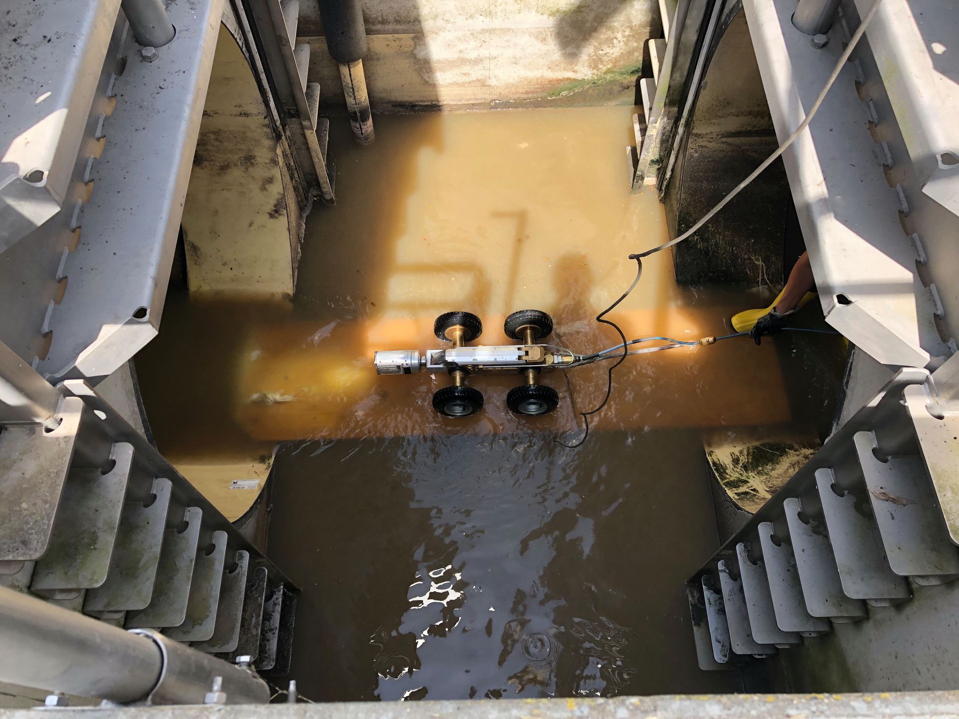Flooded industrial chamber with muddy water and a small sensor rig in the center