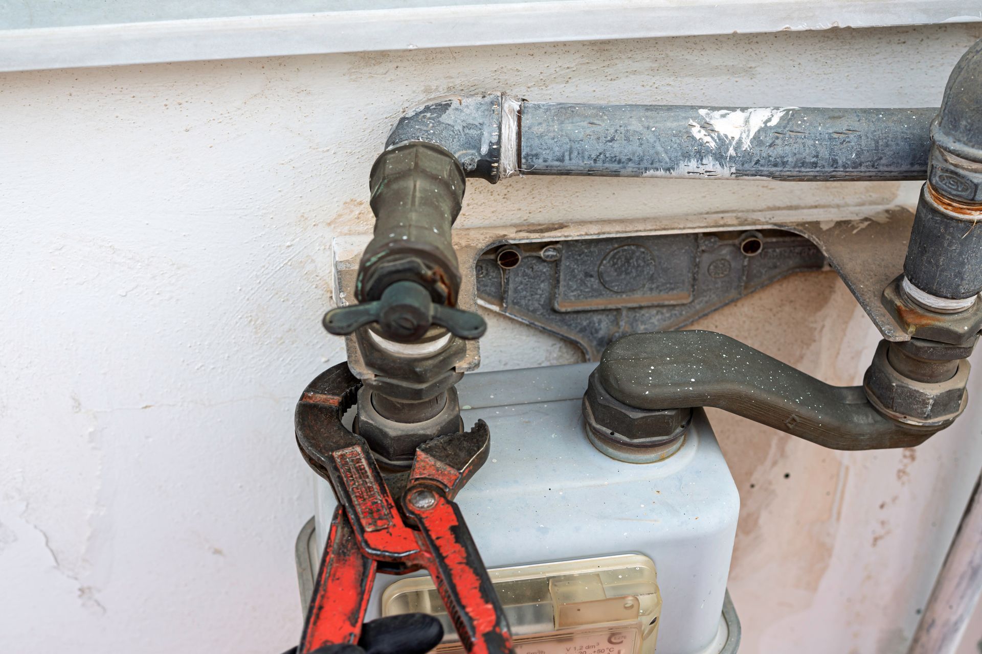 Rusty metal pipe valves with a red clamp on a white tank outdoors