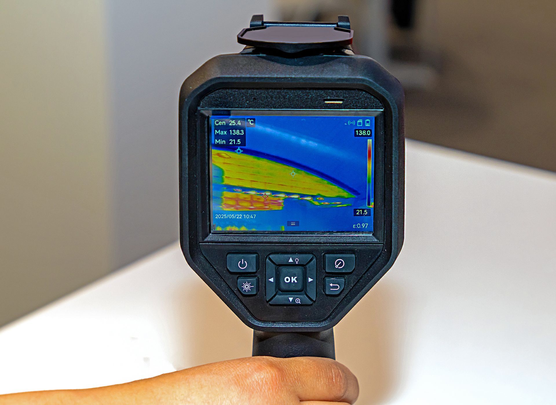 Handheld thermal camera showing a false-color heat map on its screen