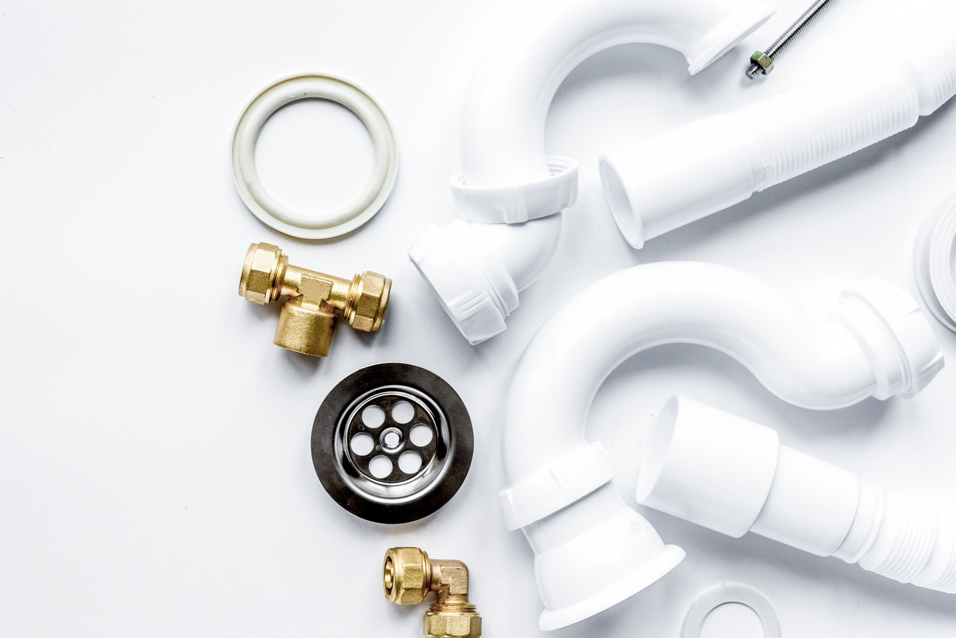 White PVC plumbing pipes, fittings, and brass connectors on a white background