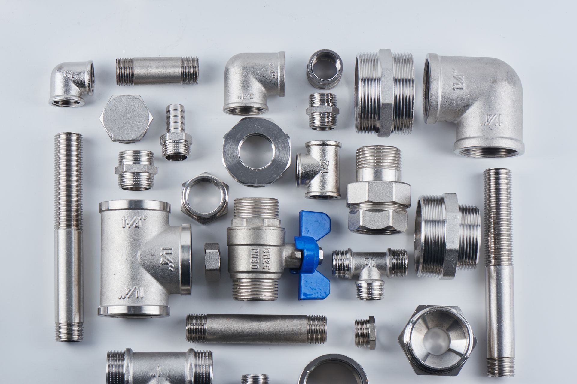 Assorted silver metal plumbing pipe fittings arranged on a white background