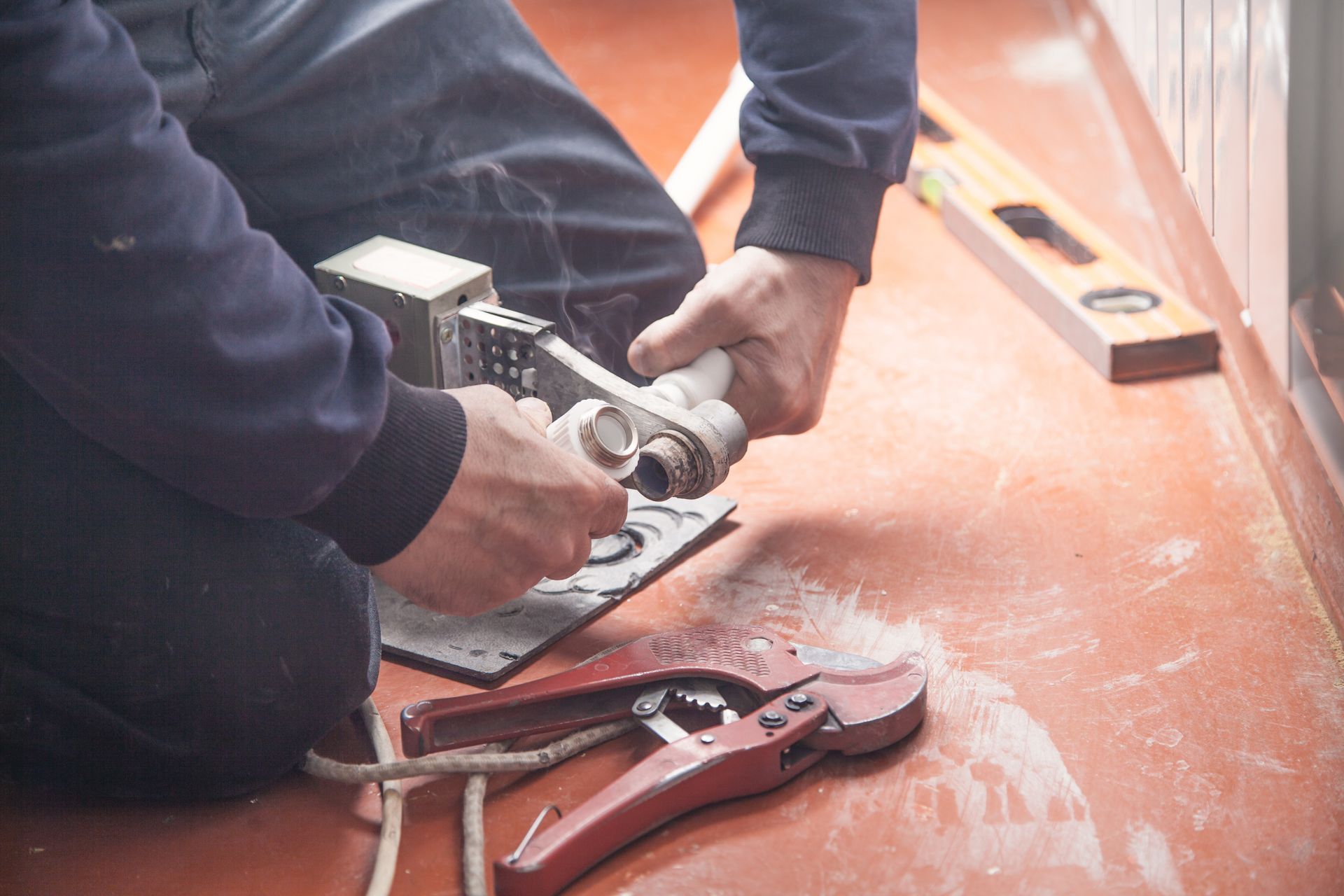 Person using pliers to adjust a shoe on a workbench with tools nearby