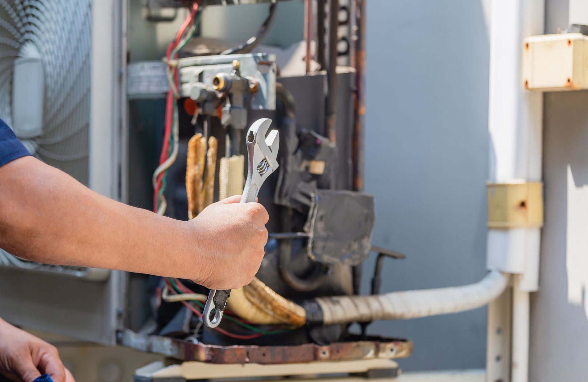 Technician using a wrench to service electrical equipment on an outdoor utility unit