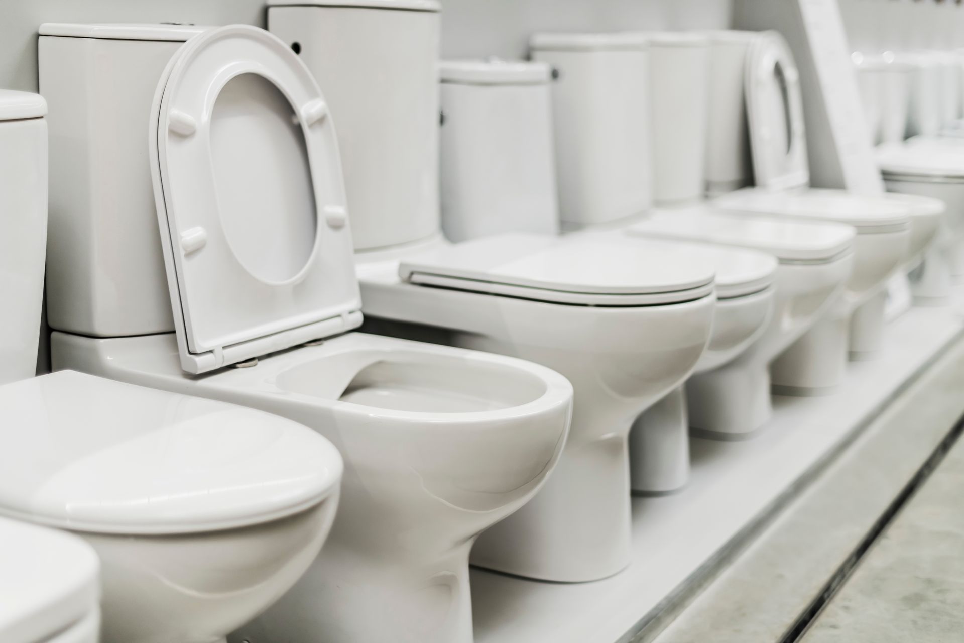 Row of white toilets and sinks displayed in a showroom or warehouse aisle