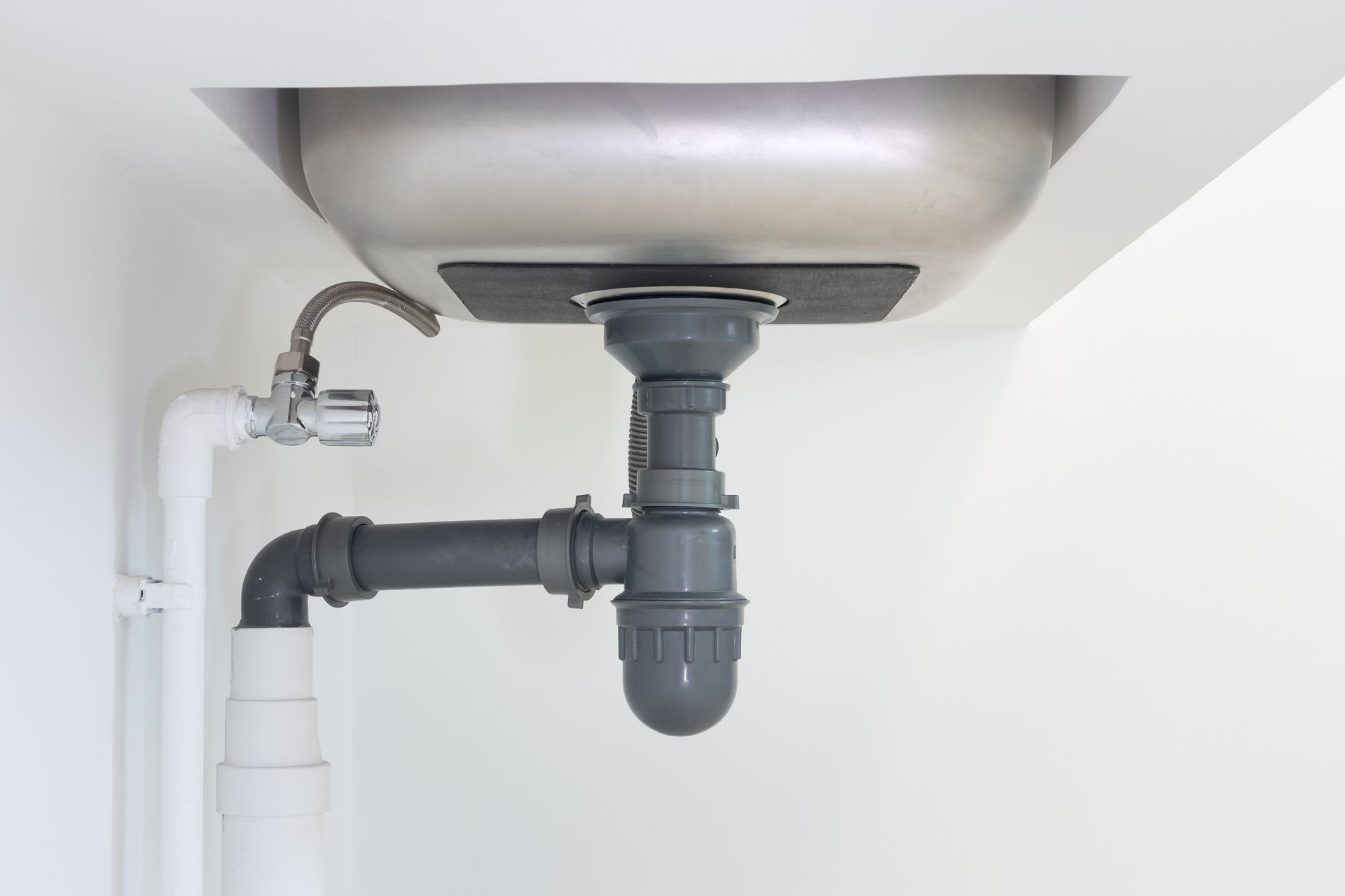 Under-sink plumbing and drain pipes beneath a bathroom sink