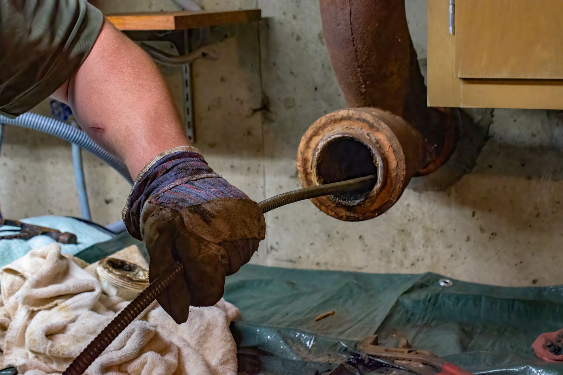 Gloved worker pulling a long rod from a furnace opening in a workshop