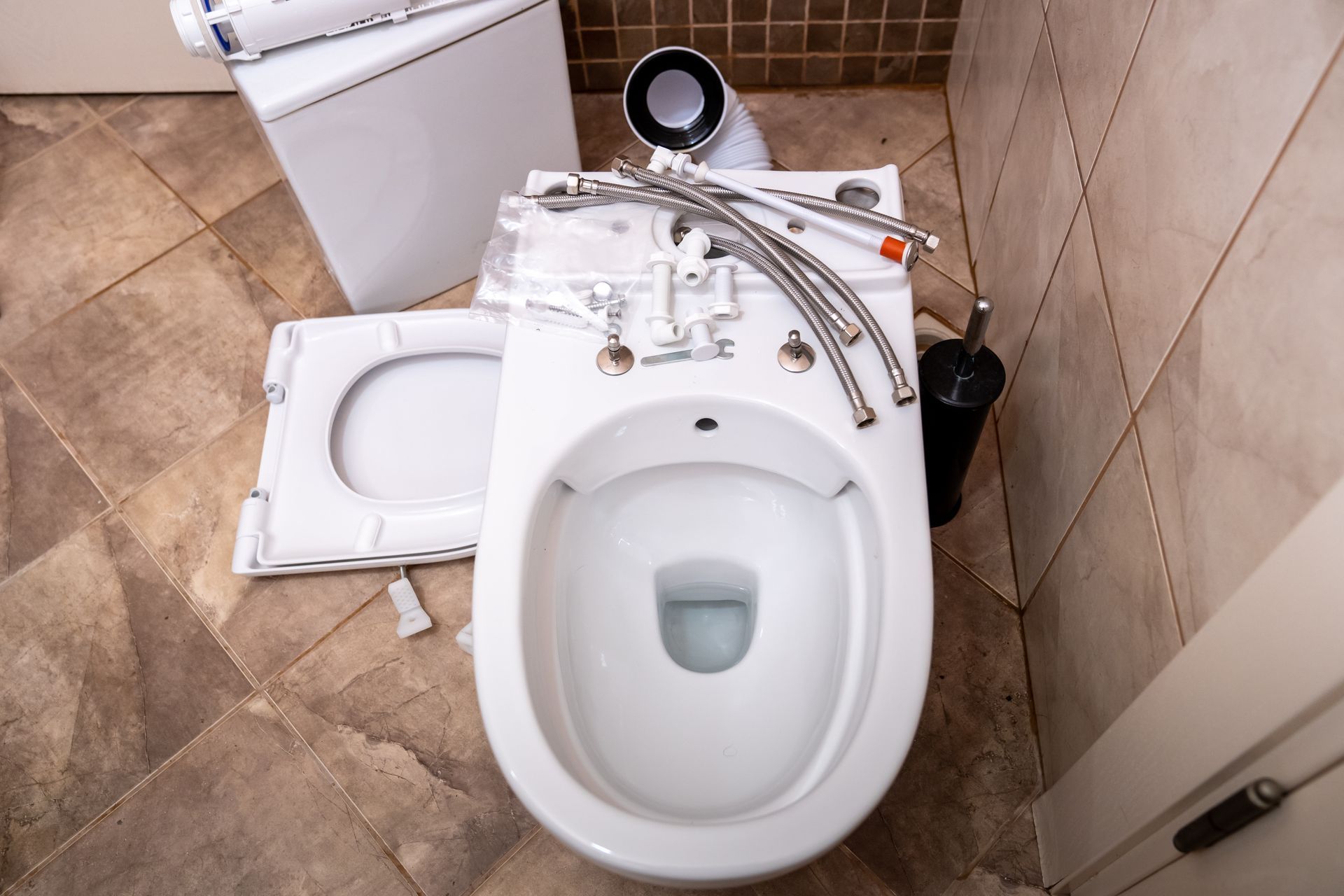 Damaged toilet in small bathroom with broken seat, loose parts, and scattered tools on the floor