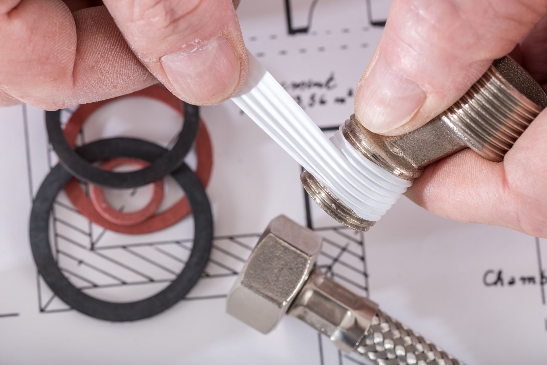 Hands attaching a silver braided hose to a metal fitting, with rubber gaskets and washers nearby.