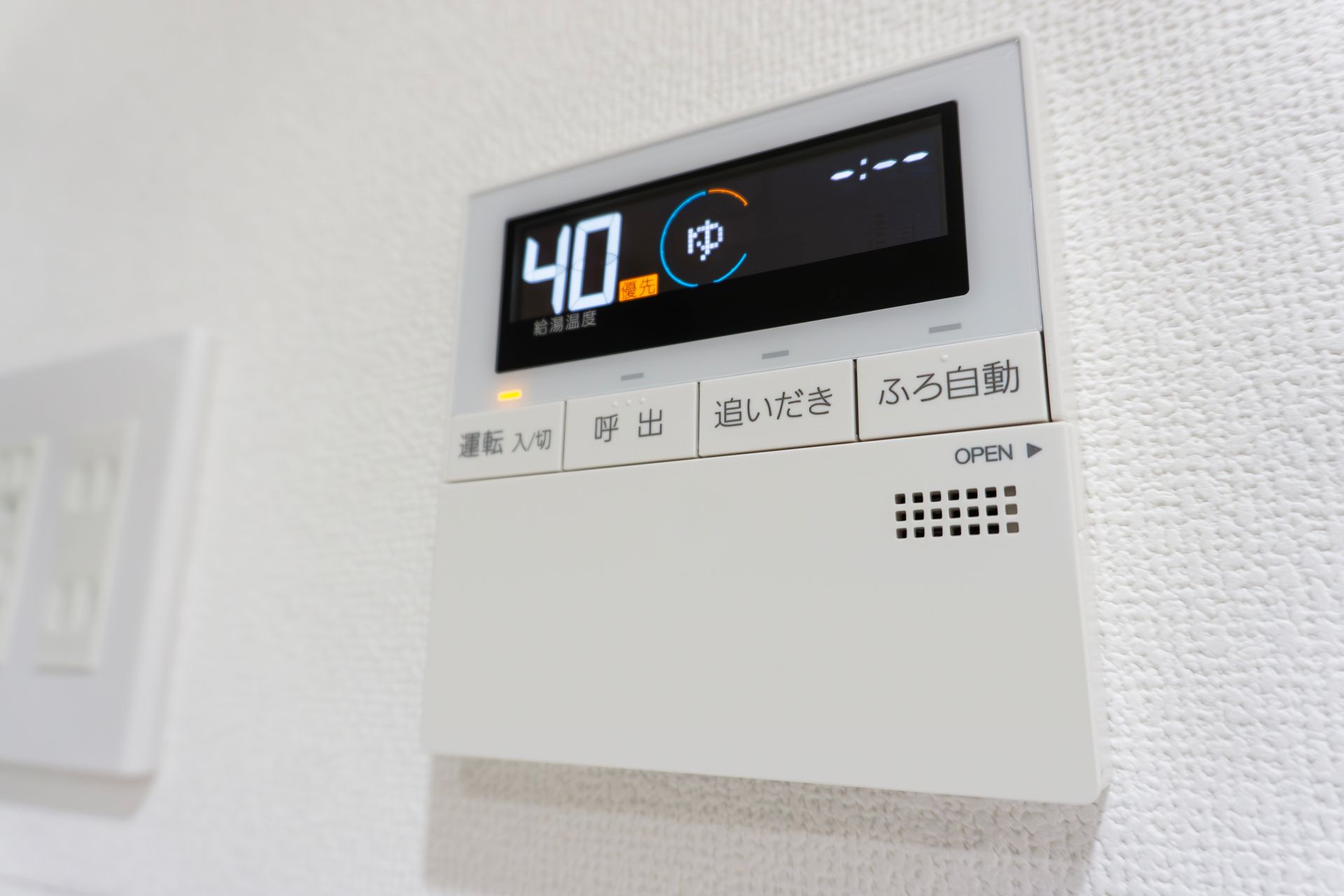 White wall-mounted thermostat/control panel displaying 40°C with Japanese labels and illuminated buttons