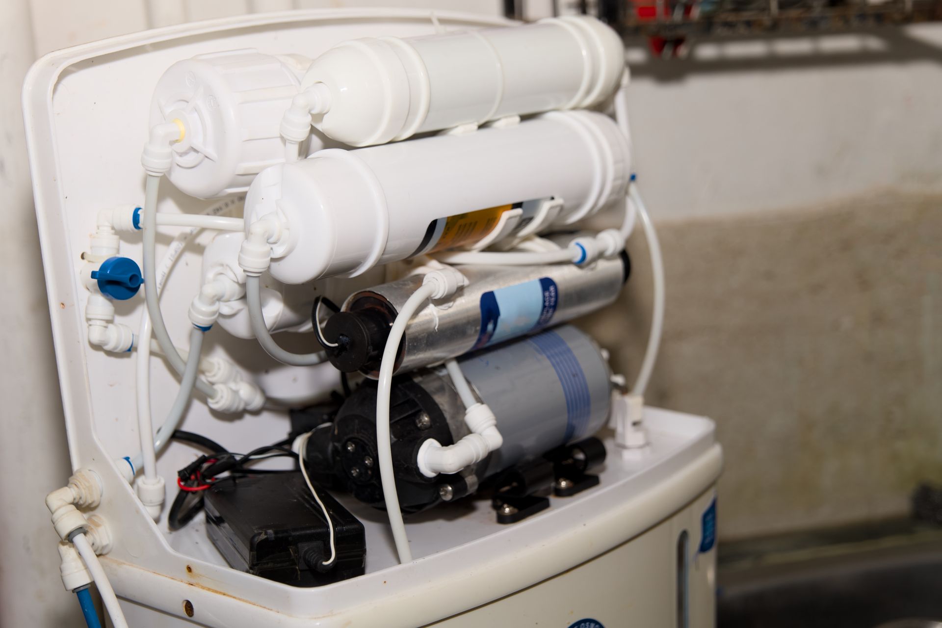 Open water purifier system with white filters and blue accents on a countertop