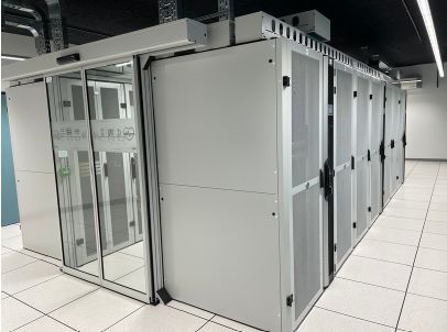 Une rangée d'armoires serveurs, intégrée à une allée de centre de données moderne avec portes coulissantes en verre et panneaux de plancher surélevés.