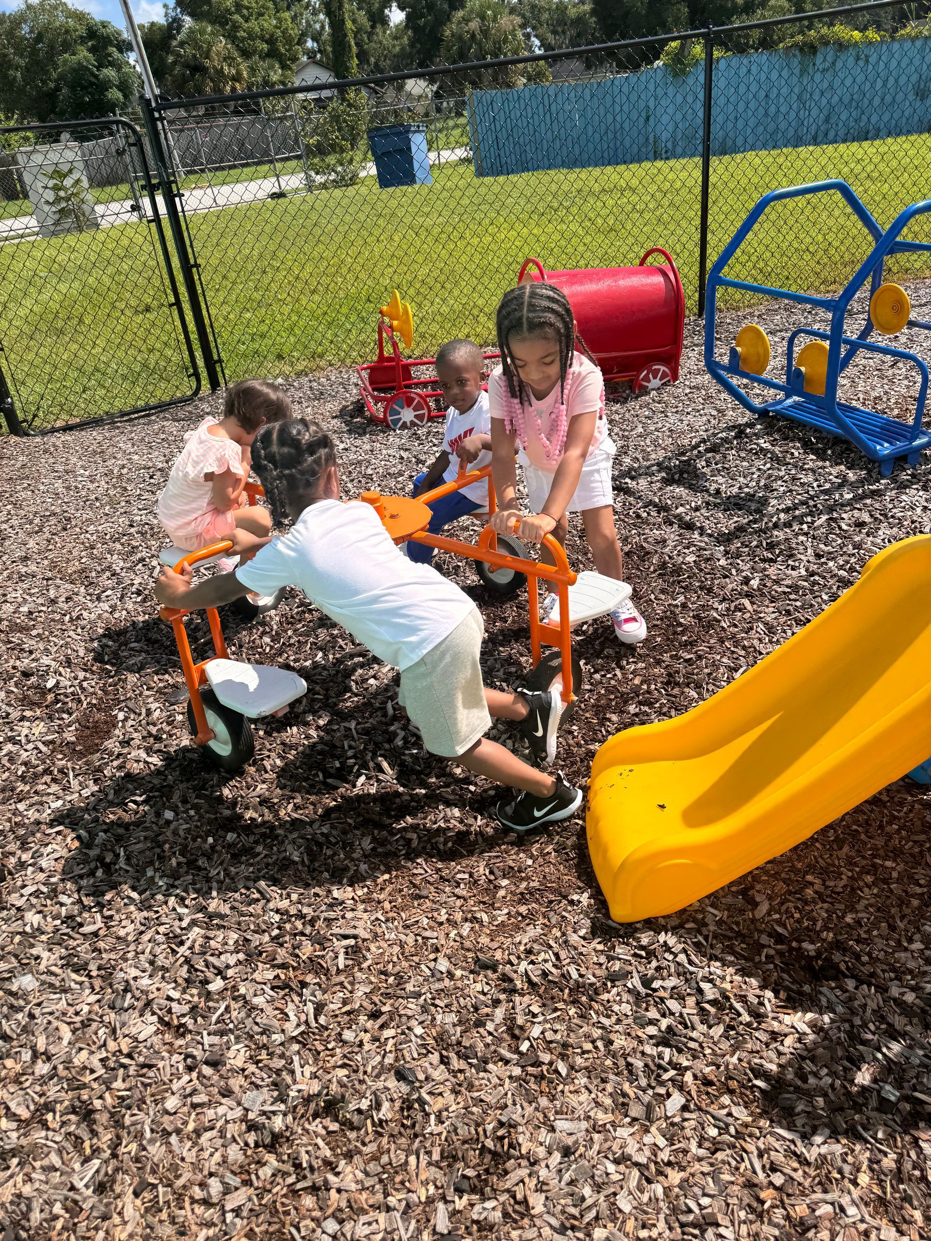 A group of children are playing on a playground with a yellow slide.