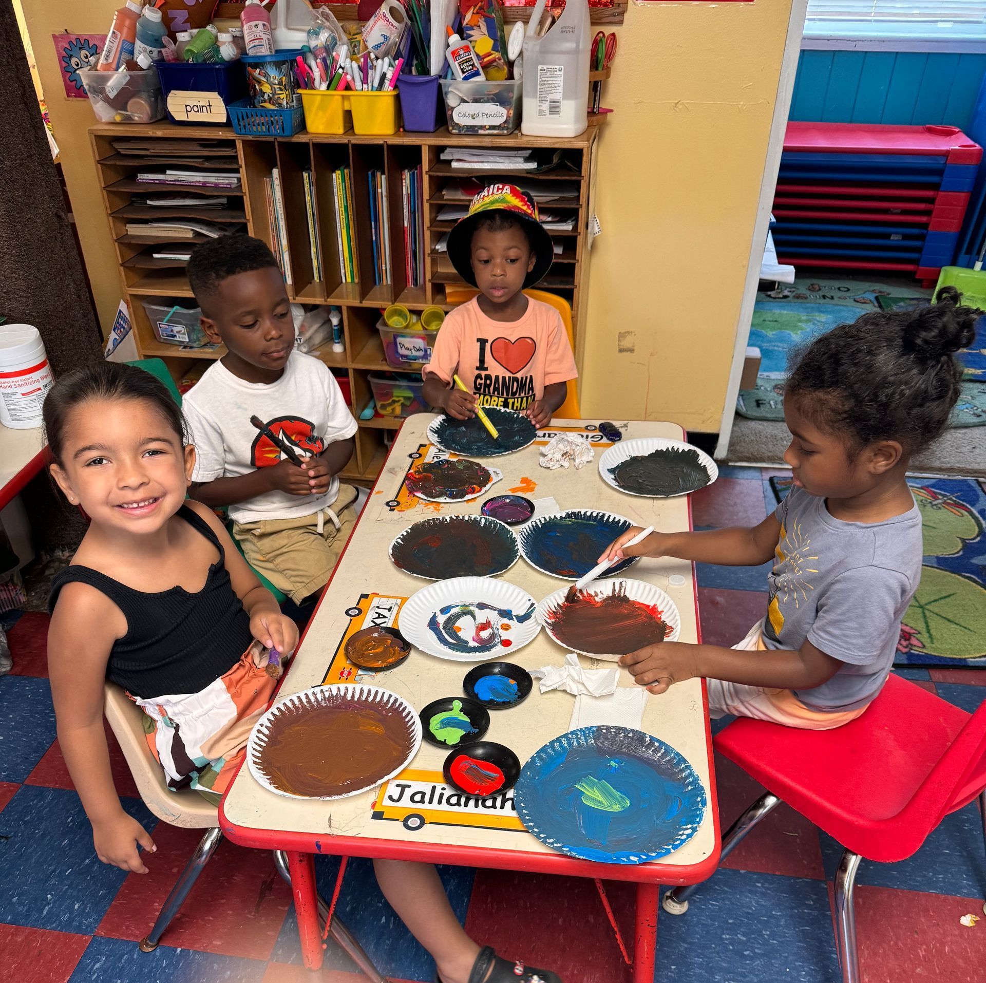 A group of children are sitting at a table with plates of food on it.