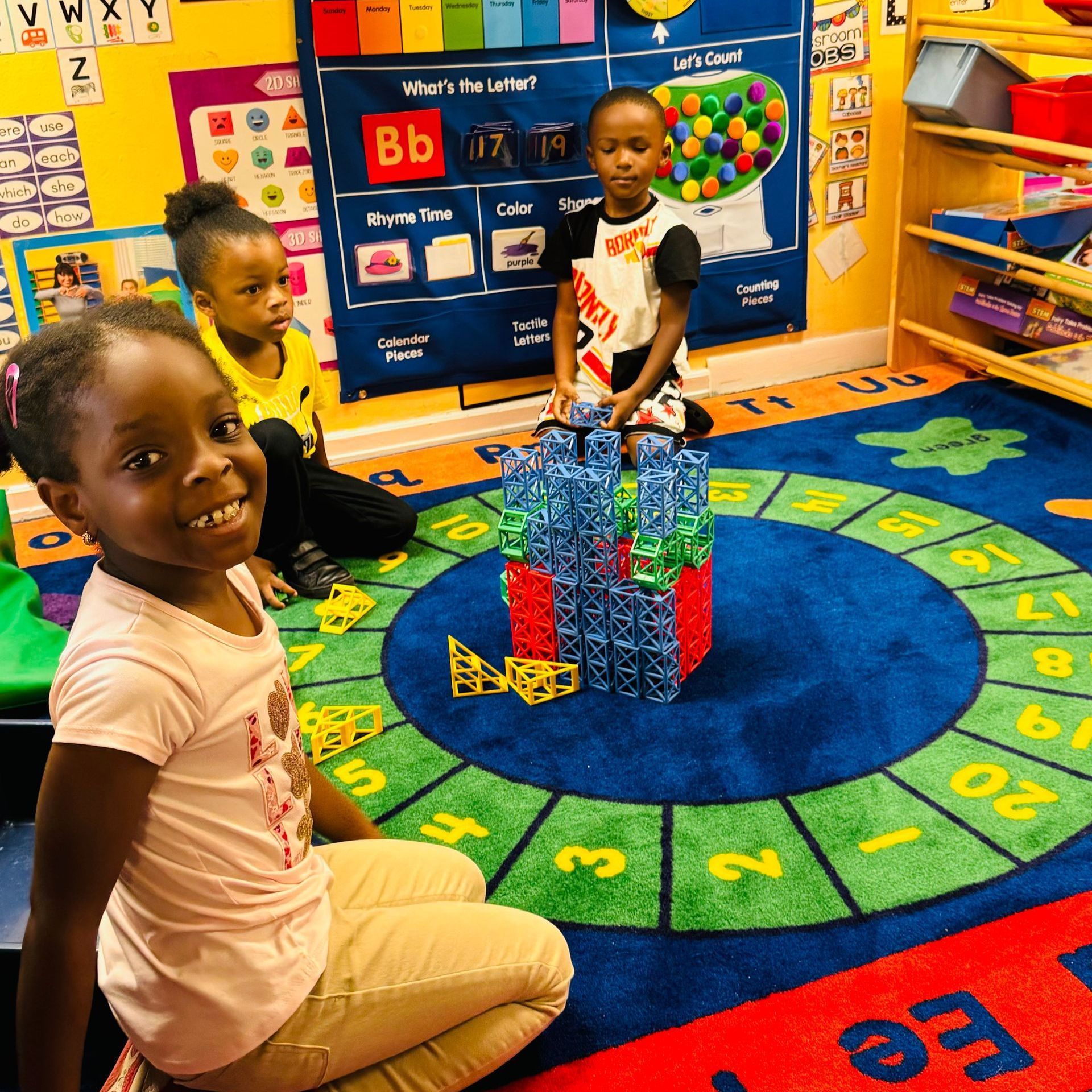A group of children are sitting on the floor in a classroom.