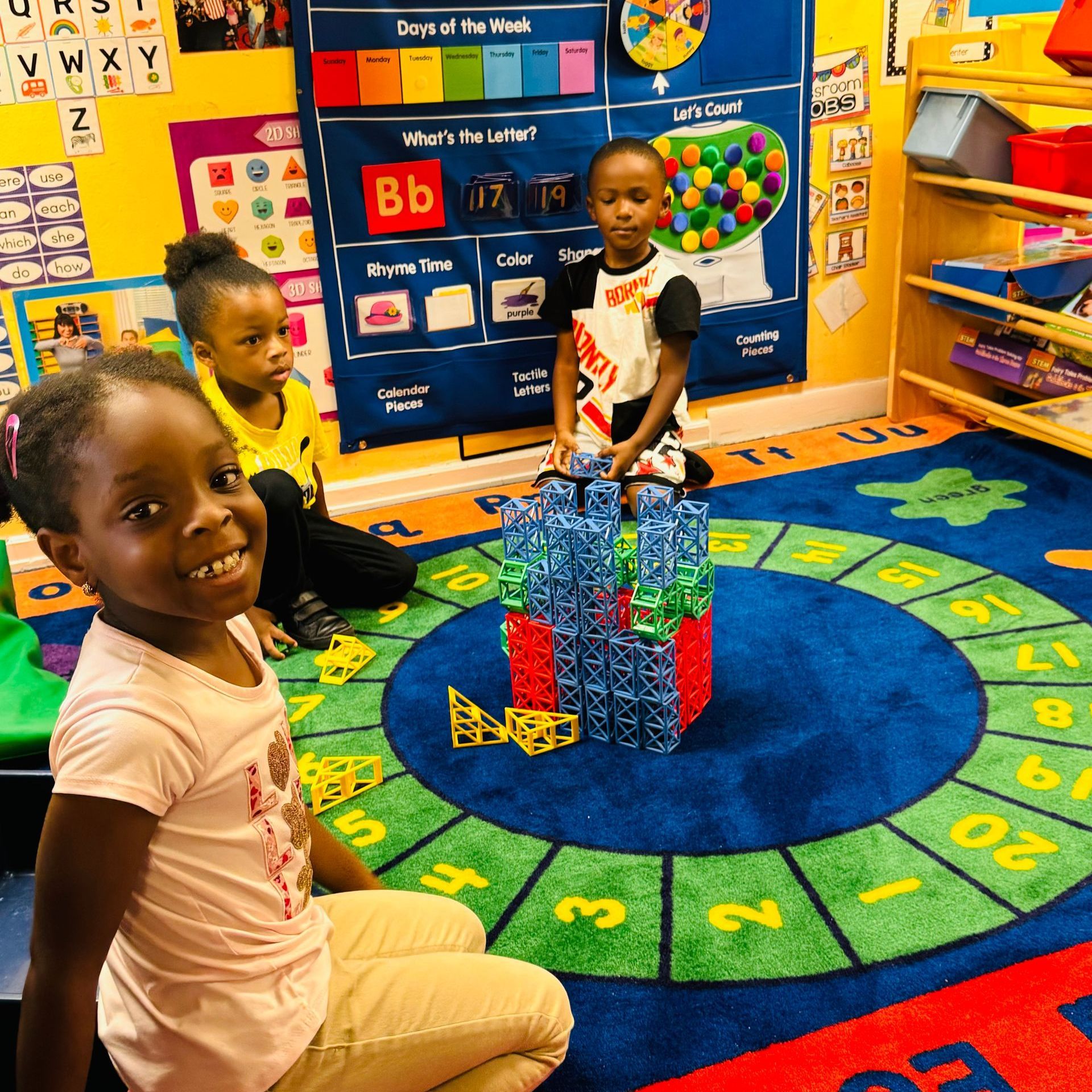 A group of children are sitting on the floor in a classroom.