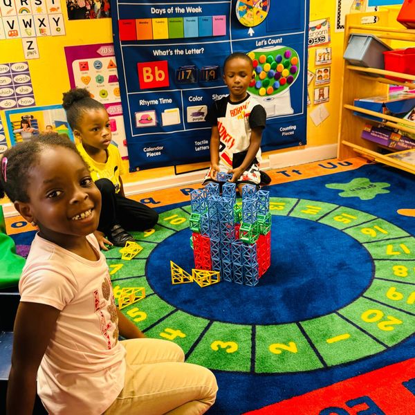 A group of children are sitting on the floor in a classroom.