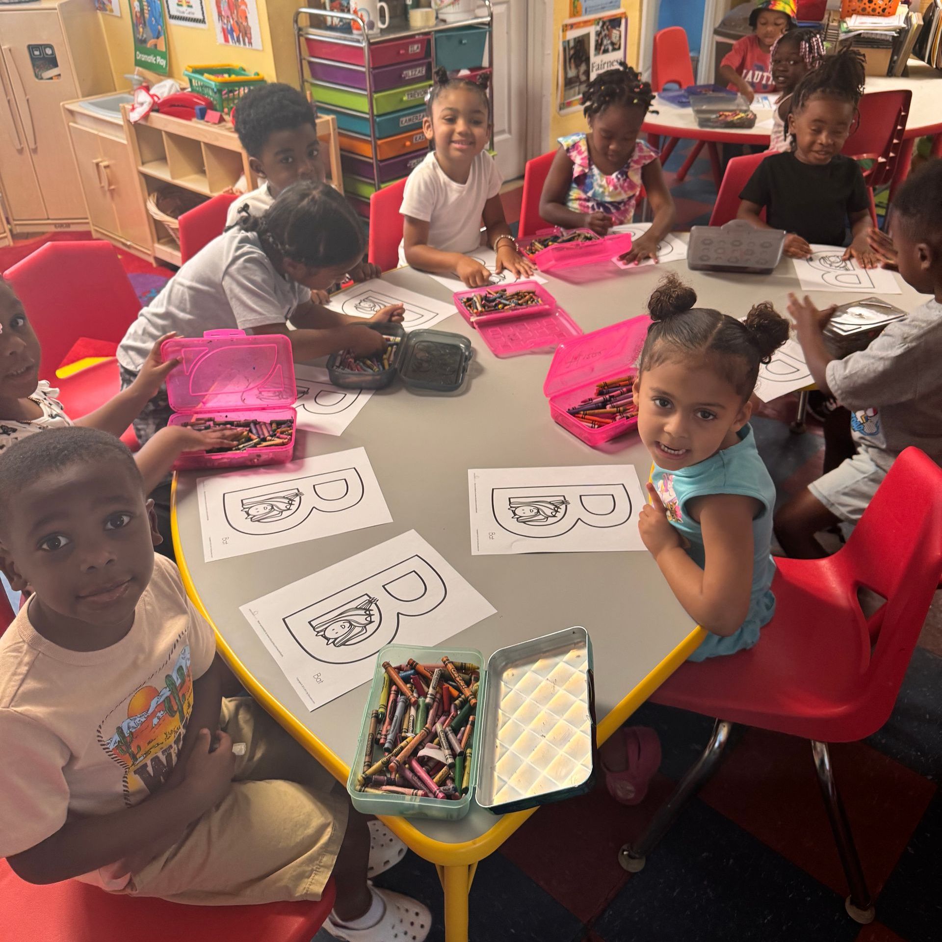 A group of children are sitting around a table with crayons