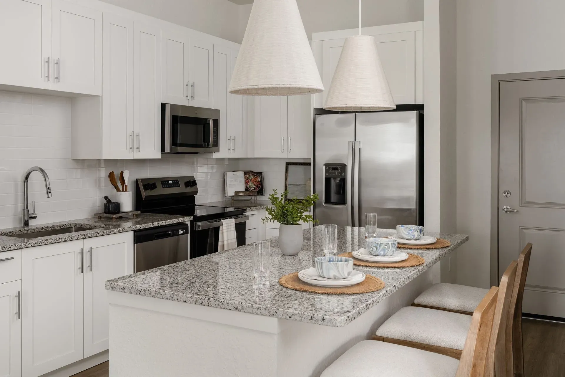 Modern kitchen with white cabinets, granite countertops, stainless steel appliances, and a breakfast bar.