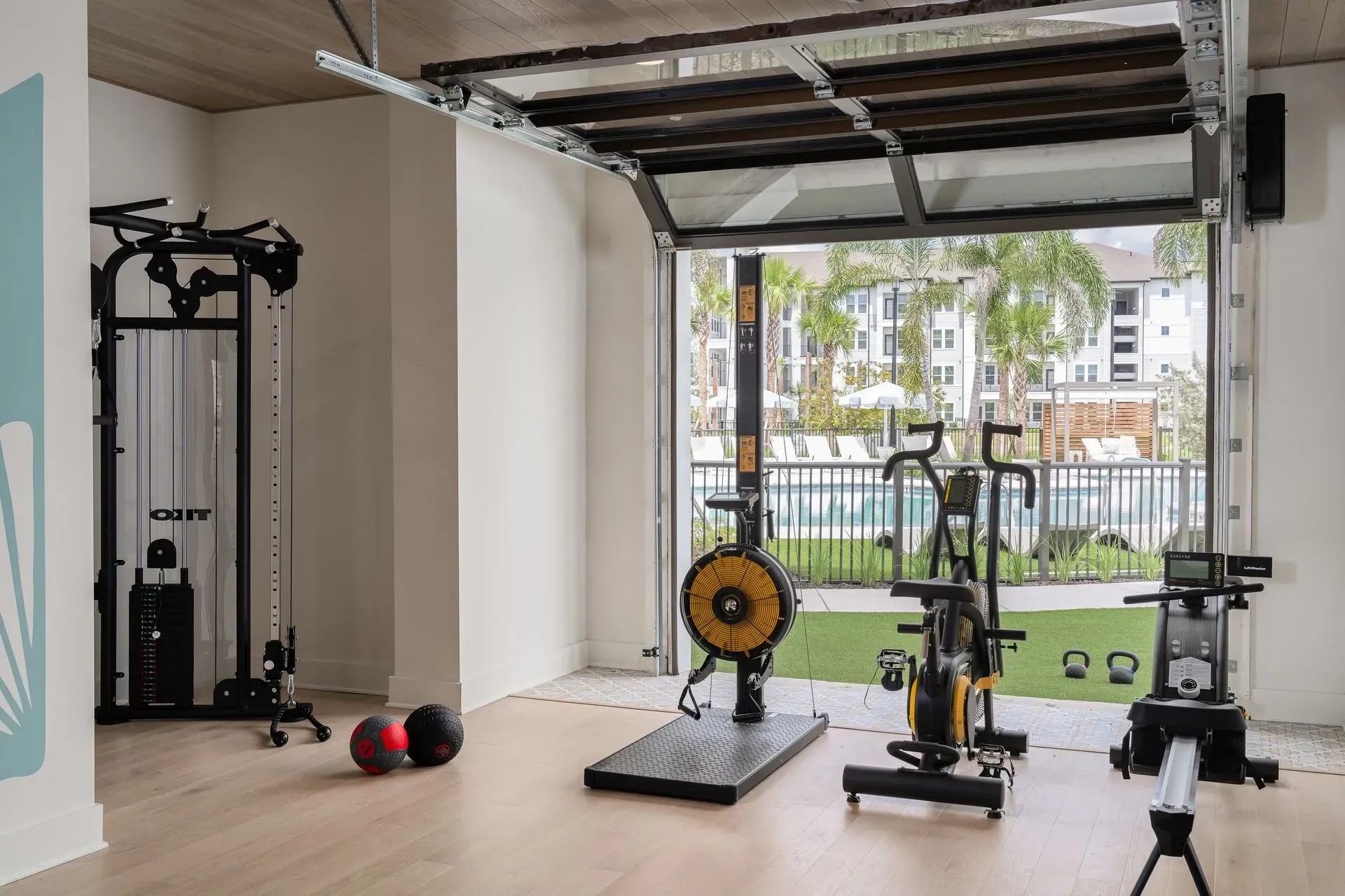 Modern gym equipment with a view of the pool and apartment buildings.