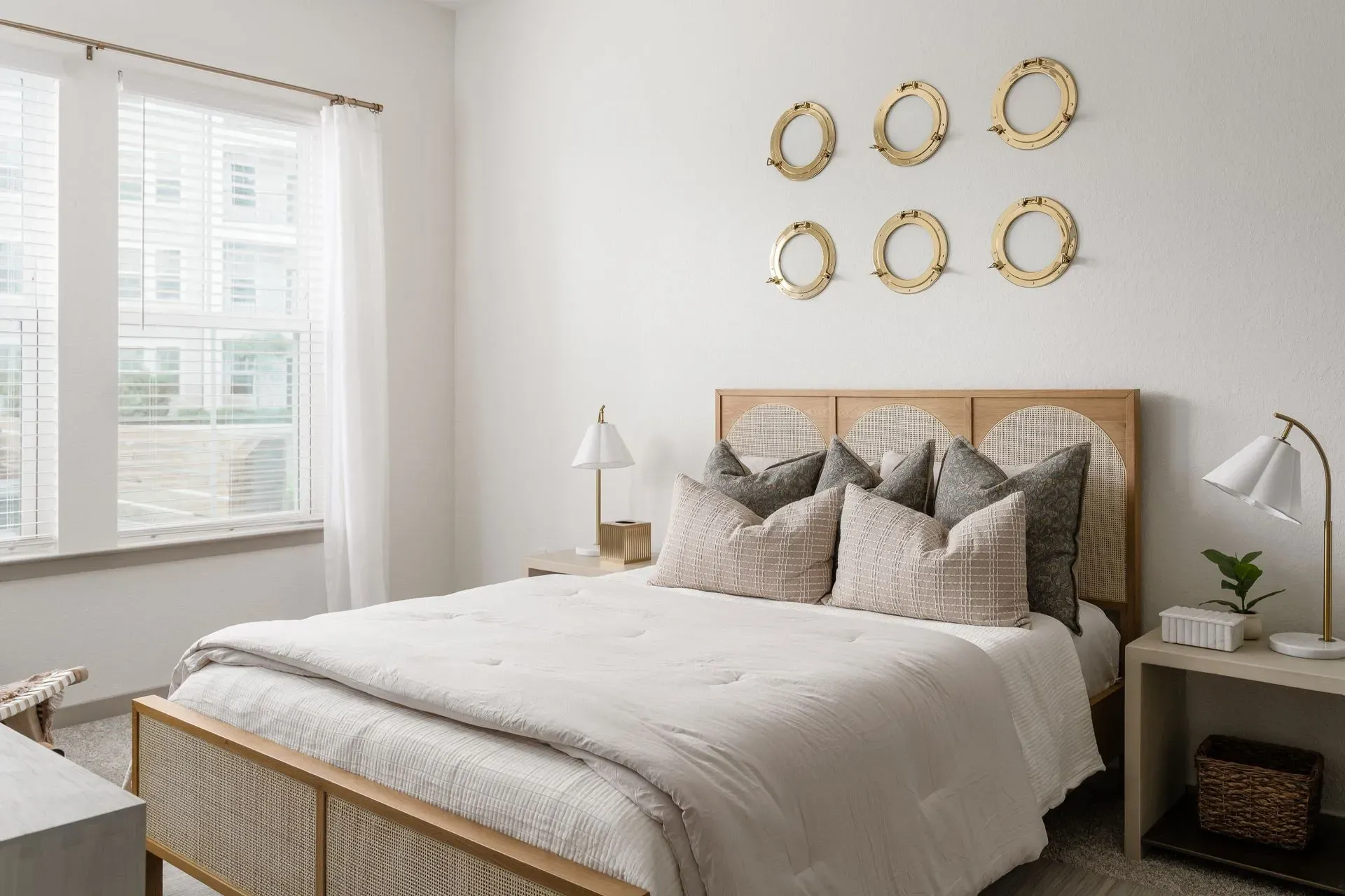 Modern bedroom with a king-size bed, neutral bedding, and decorative porthole wall art.