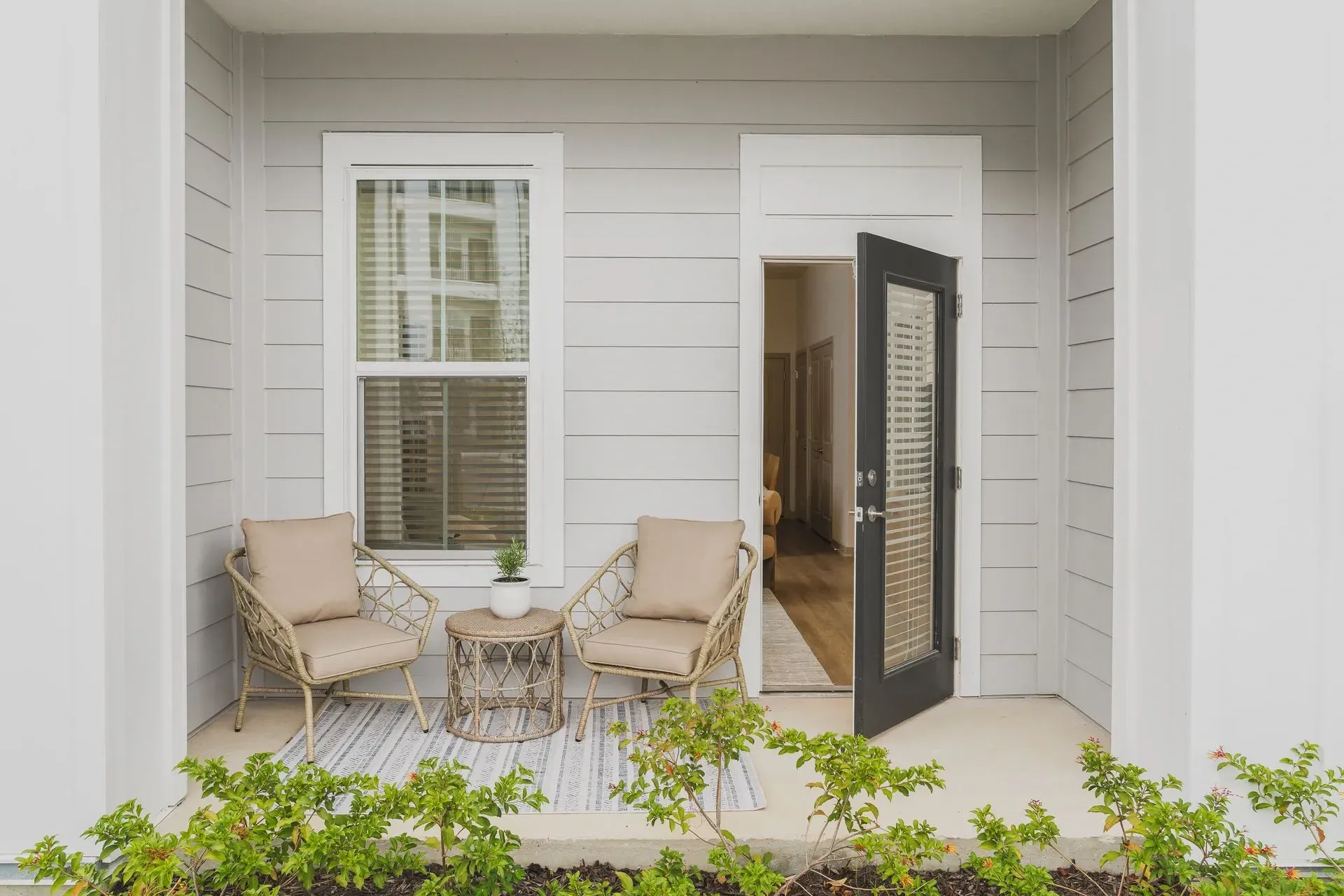 Private patio with two chairs and a small table outside an apartment door.