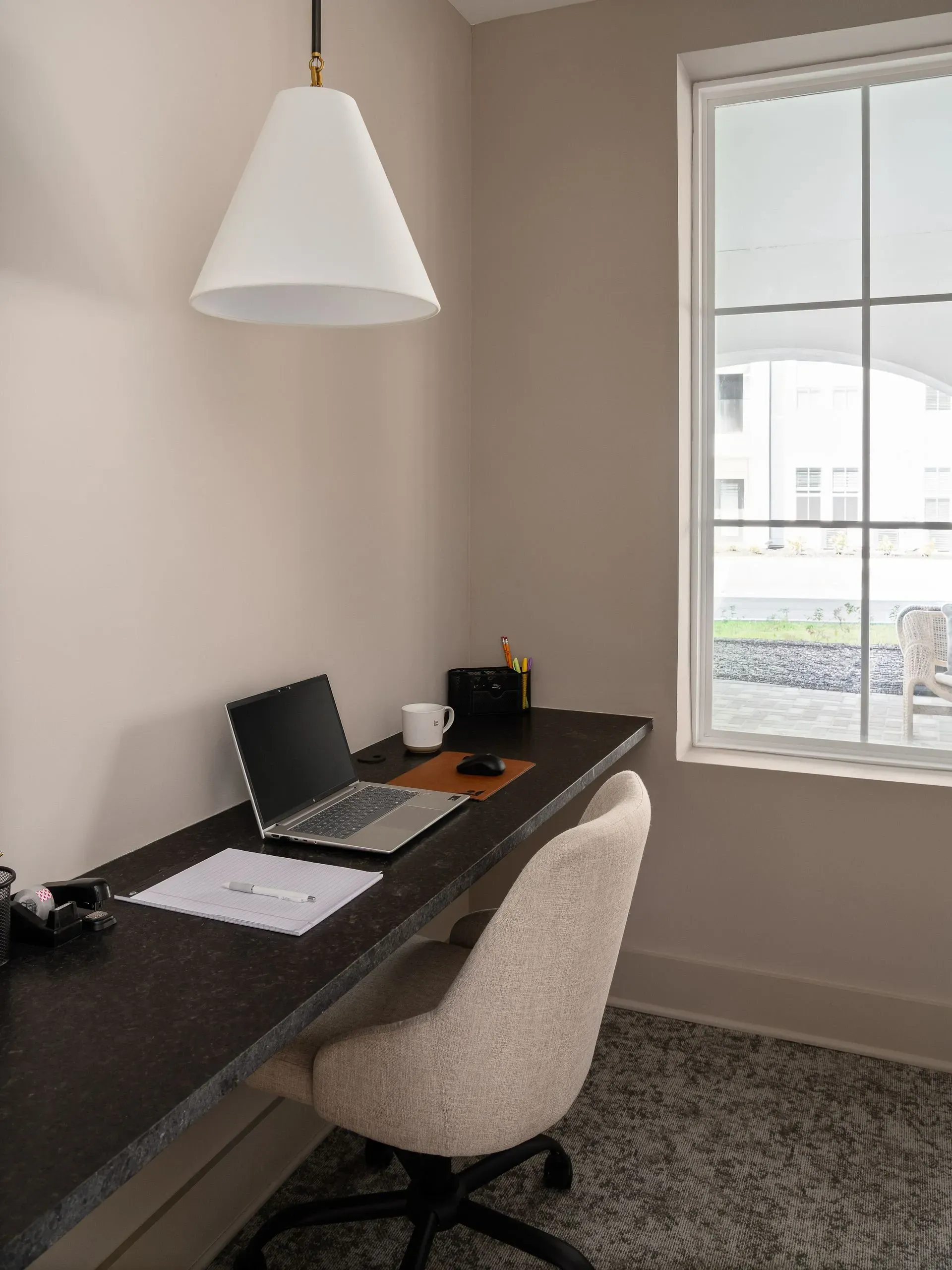 Desk with laptop, chair, and window view.