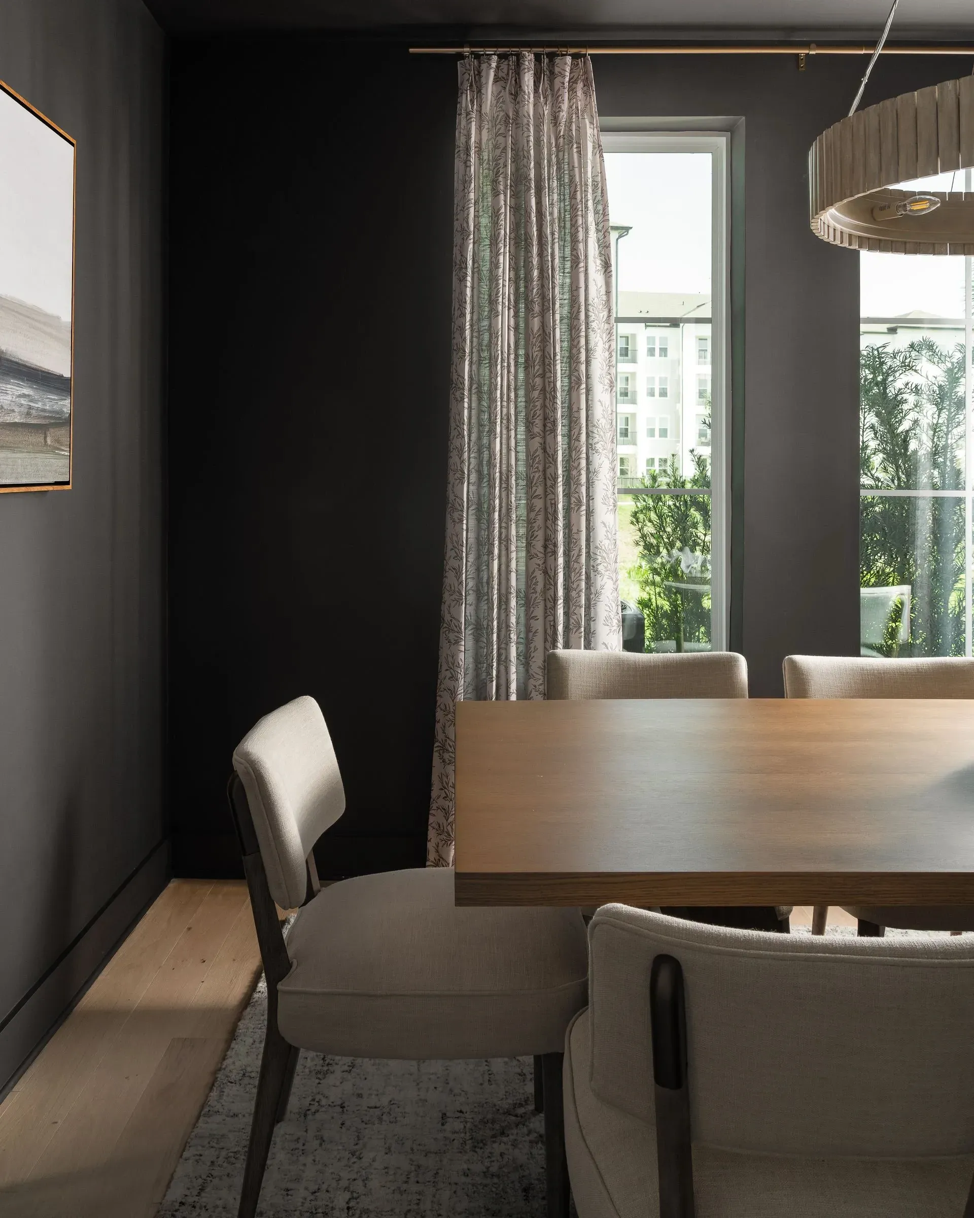 Dining room with table and chairs, window view of apartment buildings.