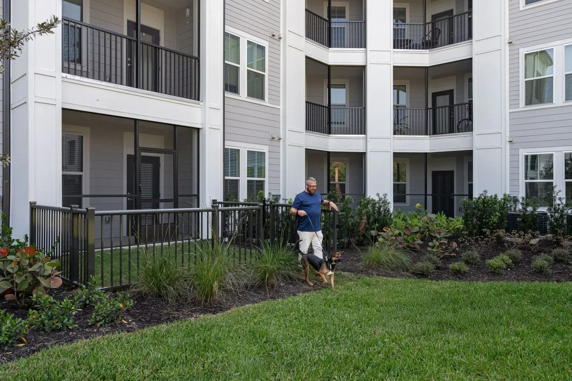 Man walking dog on leash outside apartment building