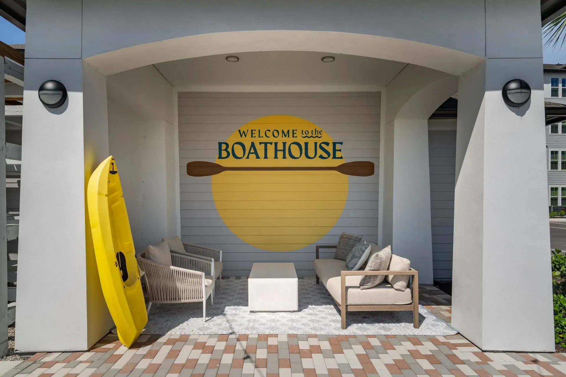 Welcome to the Boathouse signage with outdoor seating and kayak.