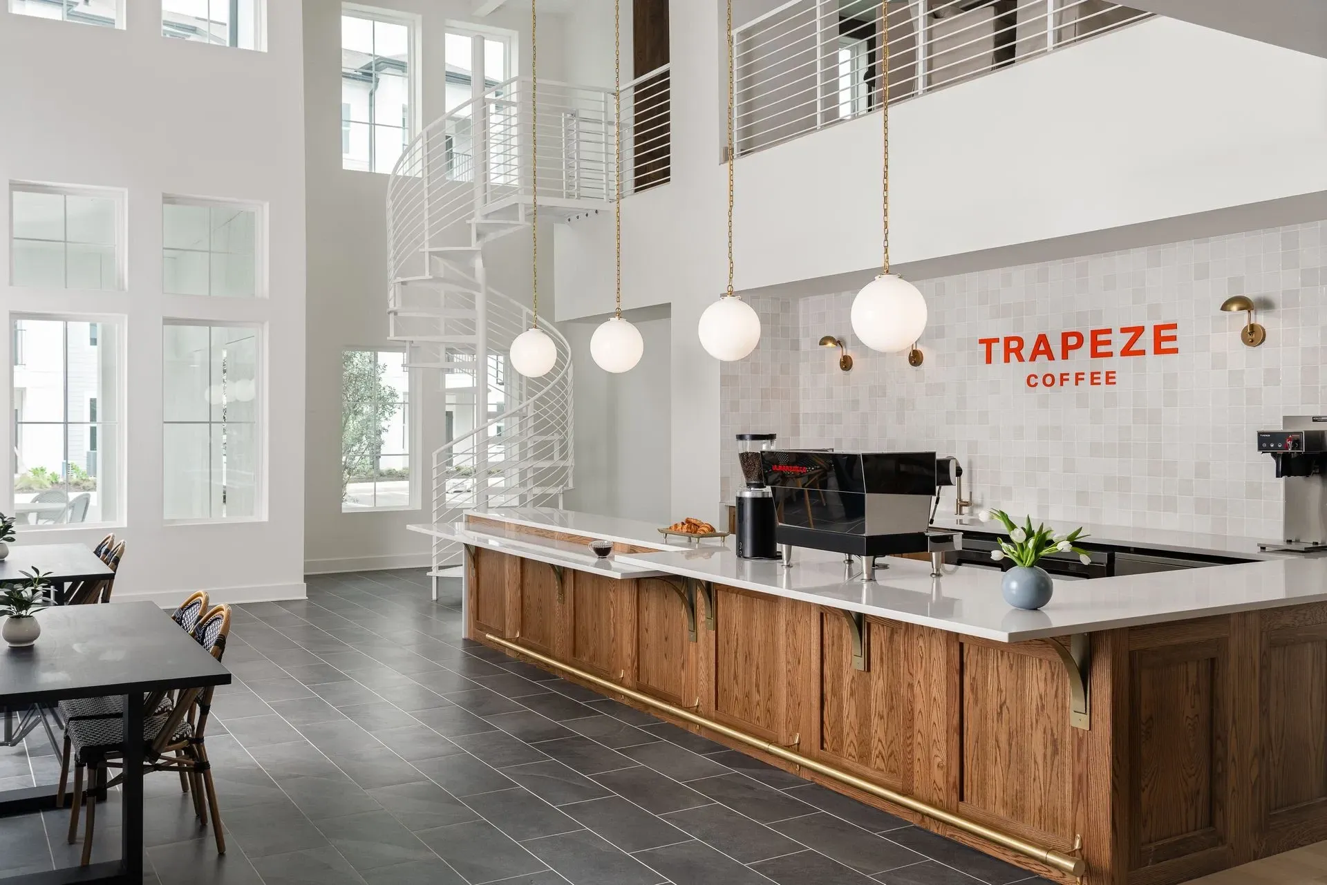 Interior of a coffee bar with Trapeze Coffee branding, spiral staircase, and seating area.