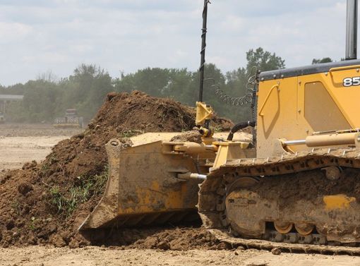 Yellow bulldozer pushing a dirt mound on a dusty construction site