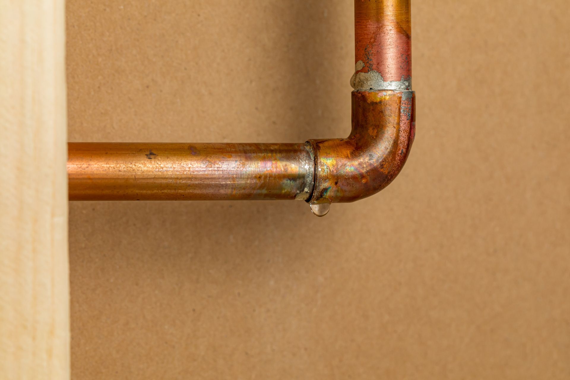 Close-up of a white water heater with gas valve, pipes, and warning label attached