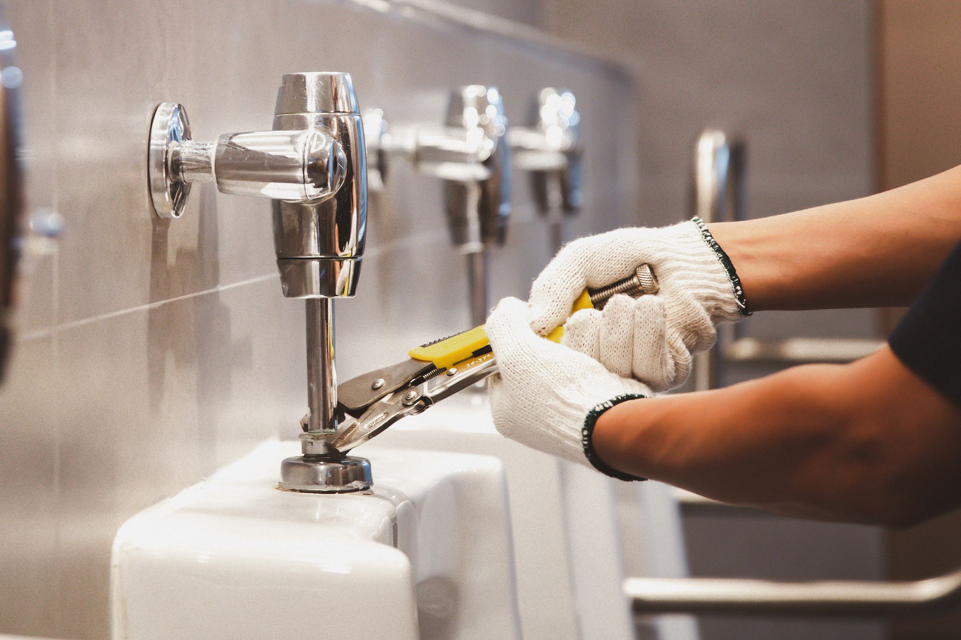 Plumber using a wrench to repair a leaking pipe under a sink sink cabinet