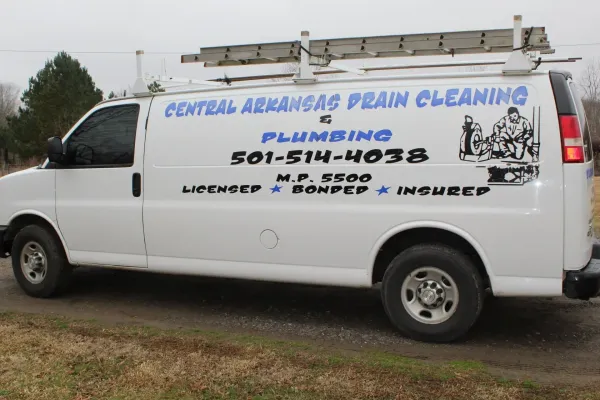 White van for Central Arkansas Plain Cleaning parked outdoors, with blue business lettering and ladder on top.