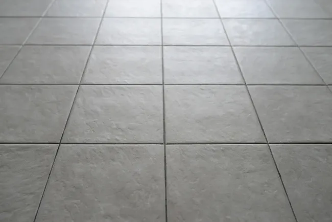 Gray tiled floor with large square tiles and grout lines, viewed from above