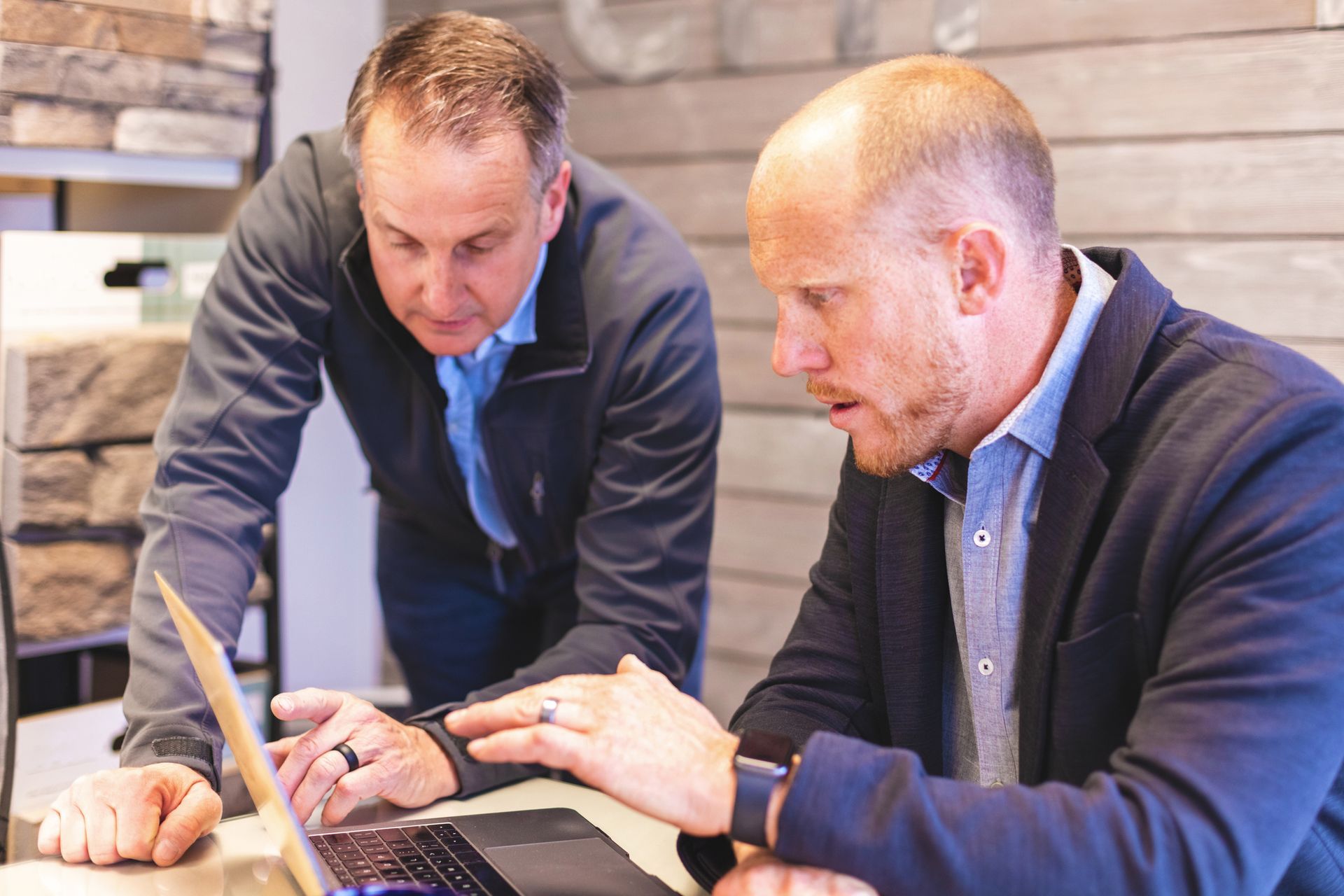 Two men are looking at a laptop computer together. Two men are looking at a laptop computer together.