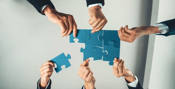 A group of people are holding blue puzzle pieces in their hands. A group of people are holding blue puzzle pieces in their hands.