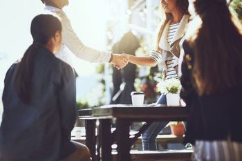 A group of people are sitting at a table shaking hands. A group of people are sitting at a table shaking hands.
