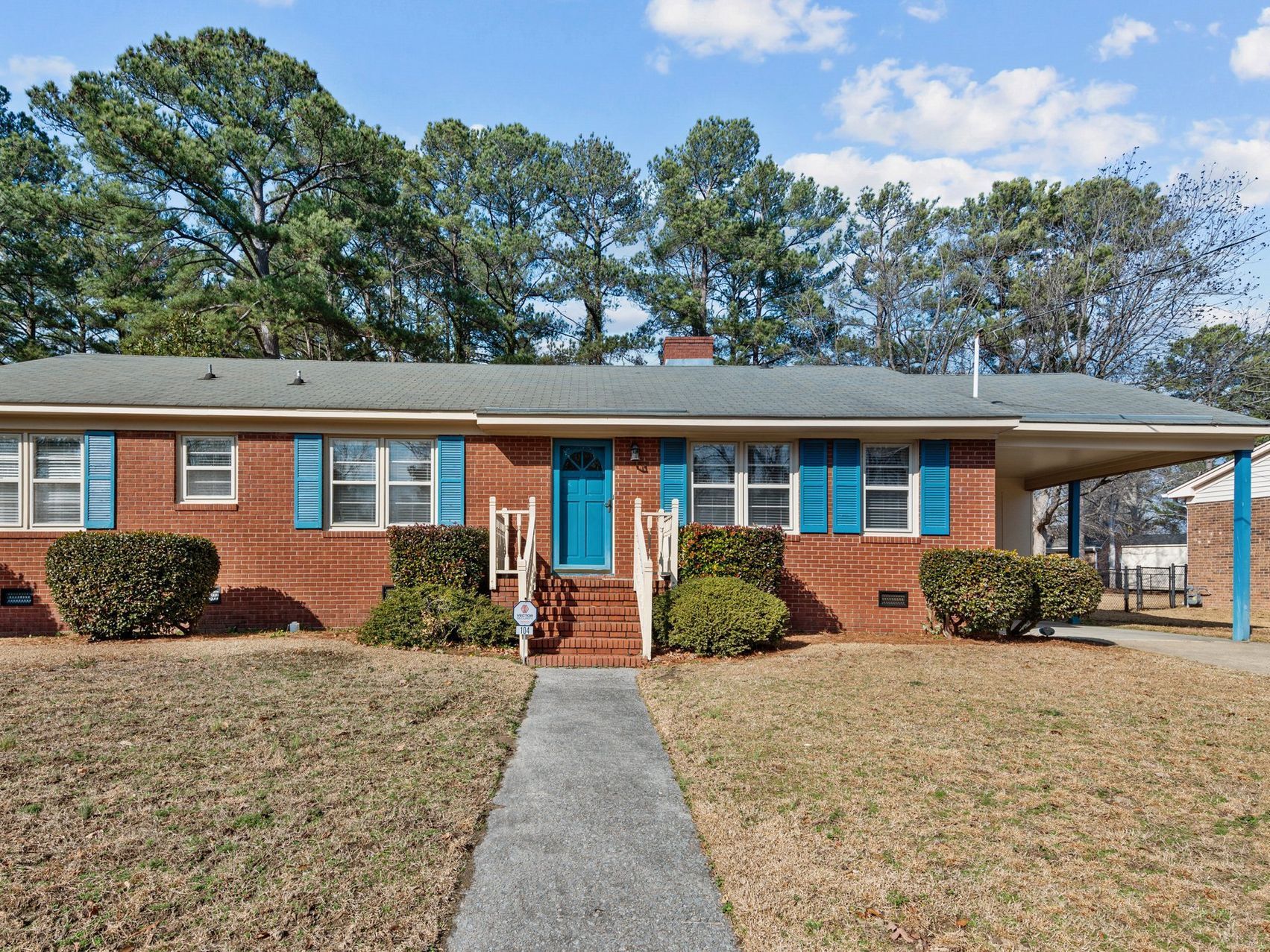 A brick house with blue shutters and a walkway leading to it.