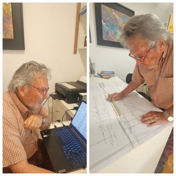 Una persona mayor revisa unos planos en un escritorio con un ordenador portátil, y luego se inclina sobre grandes hojas .