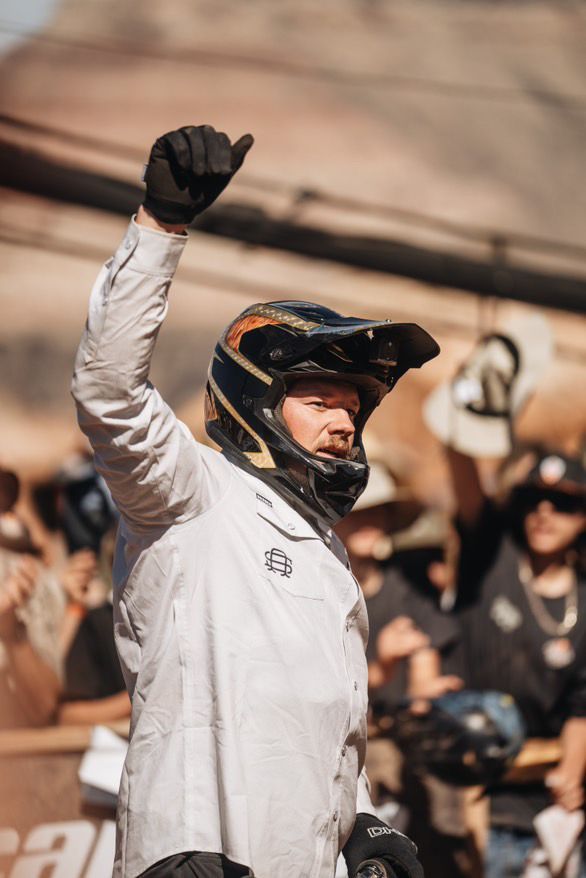 Mountain biker in helmet raises arm in victory.