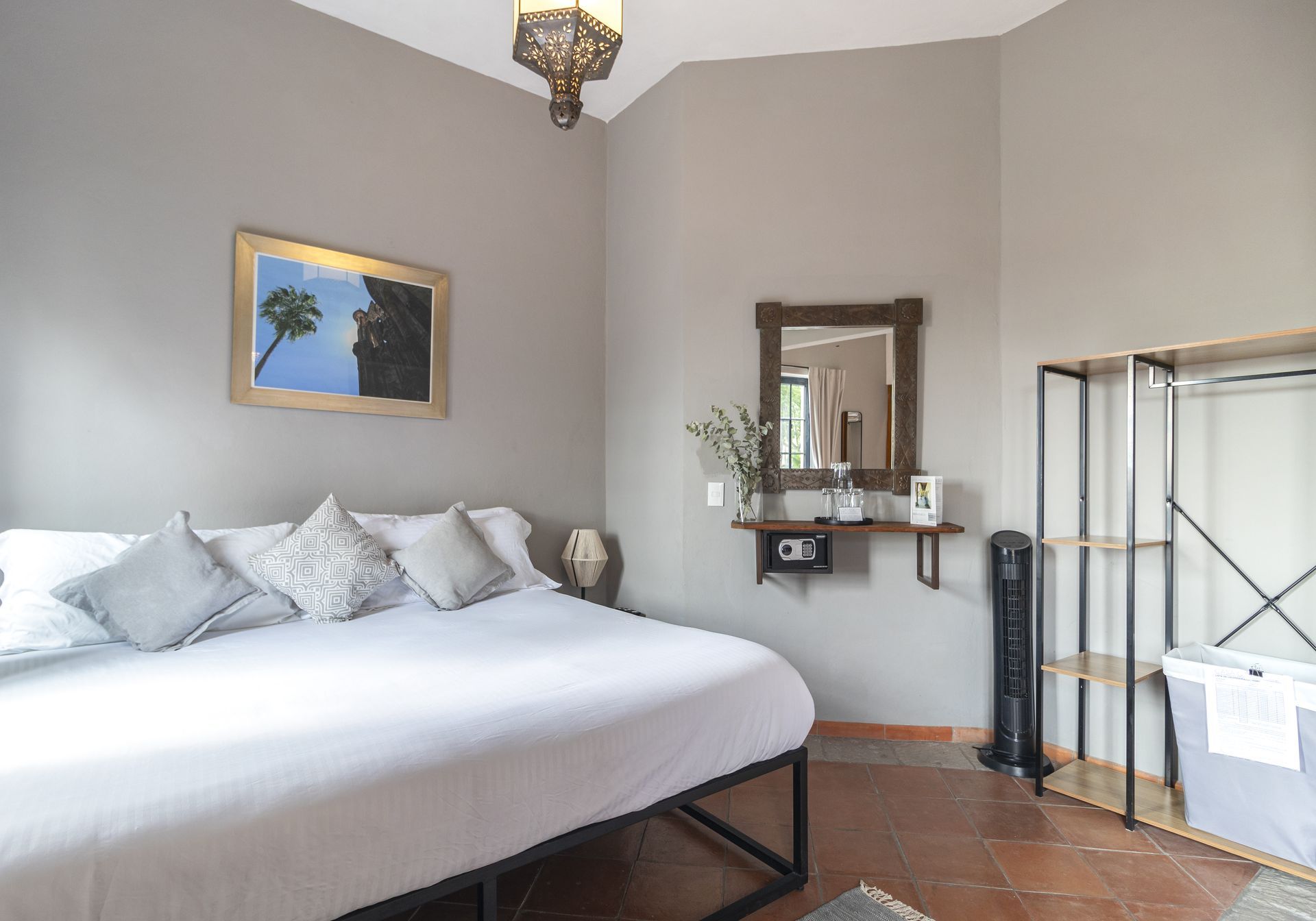 A bedroom with a king size bed , a mirror and a fan.