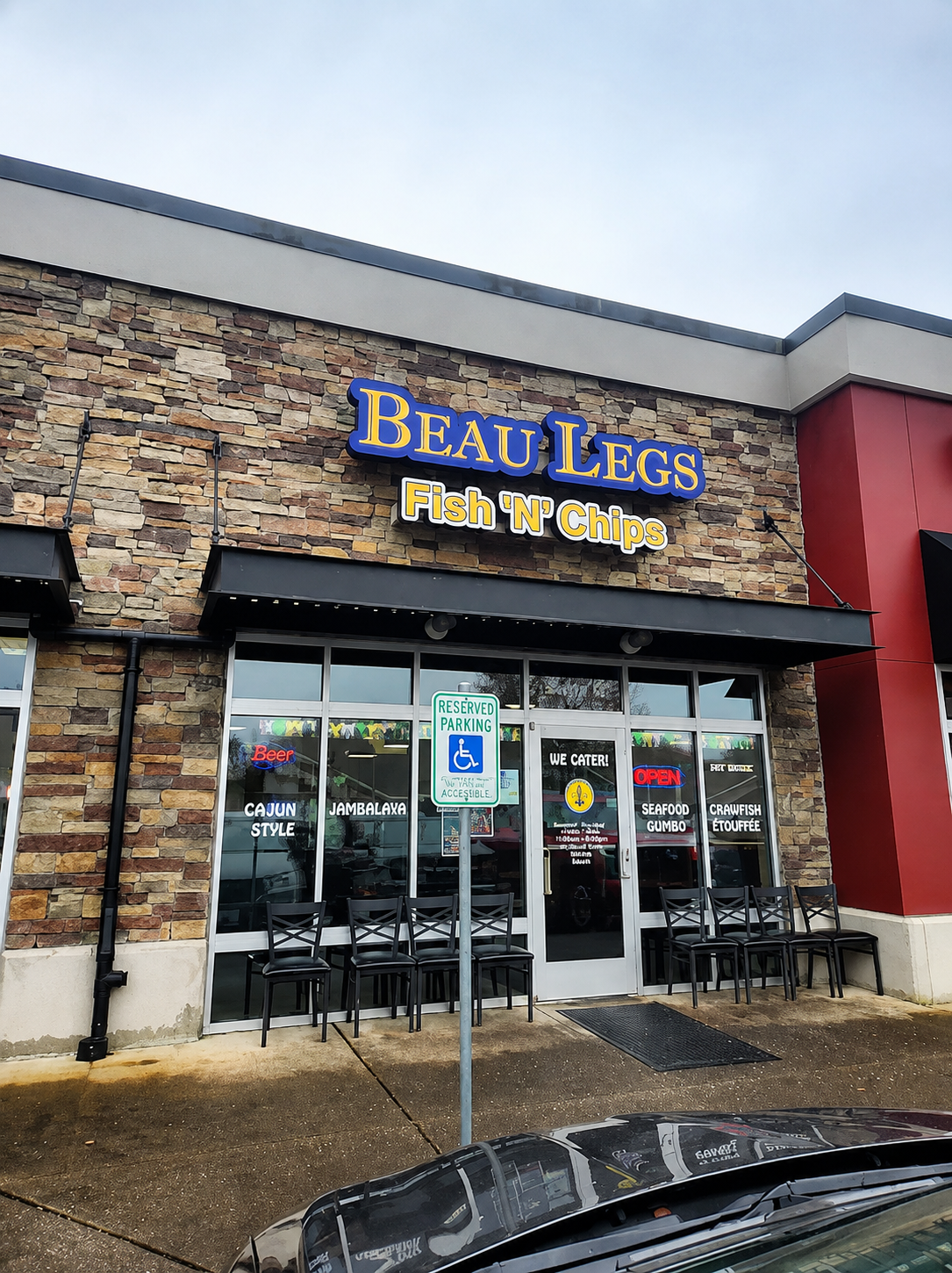 Beau Legs Fish & Chips storefront with stone facade and glass entrance under cloudy sky