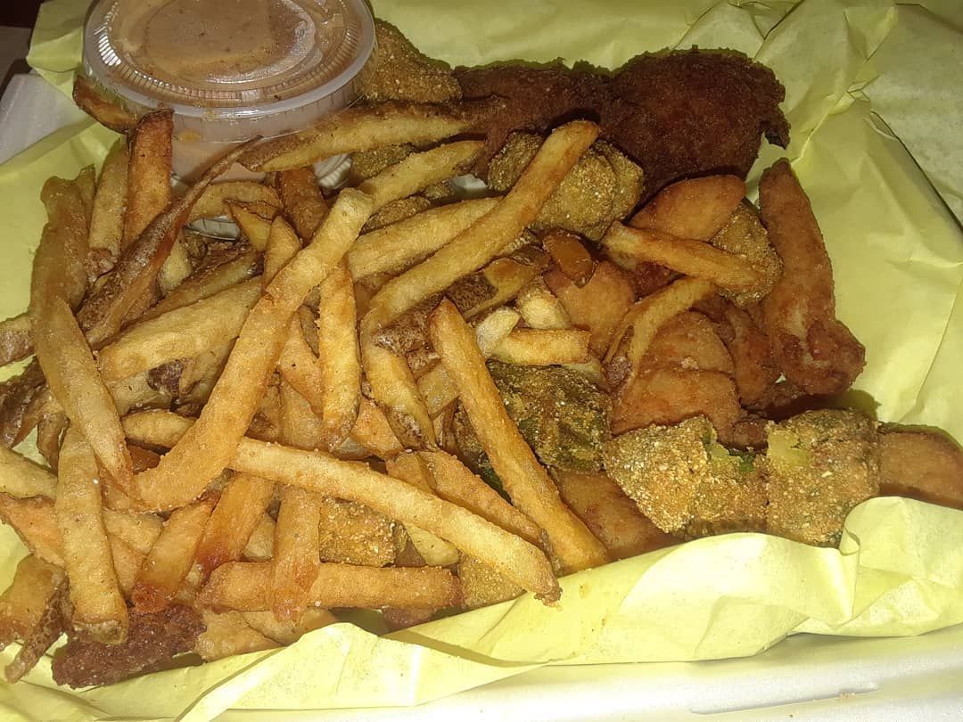 Basket of fried food: fries, chicken, vegetables, with dipping sauce.